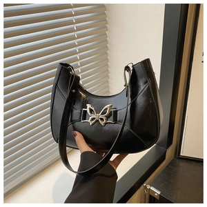 Détail du sac sous l'aisselle en cuir embossé brillant avec grand papillon argenté