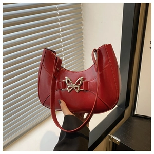 Détail du sac hobo rouge avec texture en cuir brillant et boucle papillon en métal argenté
