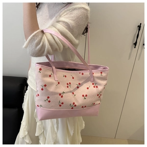 Gros plan d'un sac cabas rose avec motifs de cerises et poignées en cuir