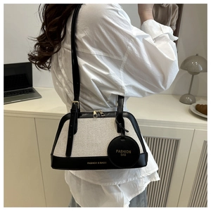 Close-up of contrast linen and black leather boston bag with elegant gold branding