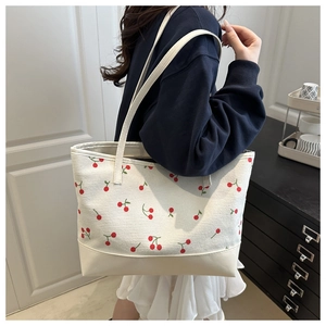 Détail d'un sac cabas beige à motif cerise et base en similicuir blanc sur modèle