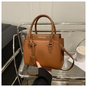 Détail du sac à bandoulière marron texture litchi avec boucle dorée et texte de mode