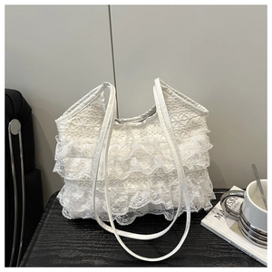 Detail of white lace tote bag with tiered ruffles and delicate mesh texture for summer