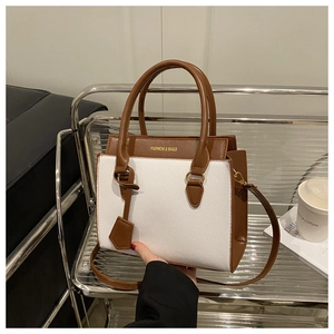 Détail du sac bandoulière bicolore en cuir blanc grainé avec des finitions en cuir brun