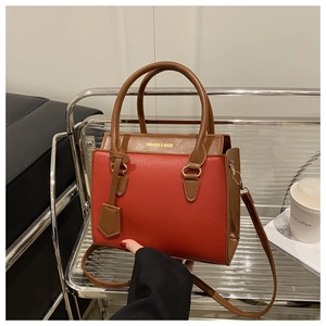 Détail d'un sac à main bicolore en cuir avec texture litchi rouge et anse marron