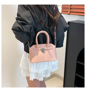 Detail van roze schelptas in generfd leer met zilveren gesp gedragen door een model