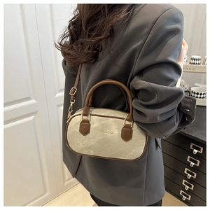 Close-up of retro bowling bag in sage green with brown leather handles and gold hardware