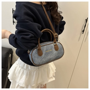 Détail du sac Boston en denim et cuir avec bandoulière réglable et lettrage de mode