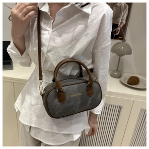 Detail view of a vintage Boston bag in grey canvas and brown leather on a model