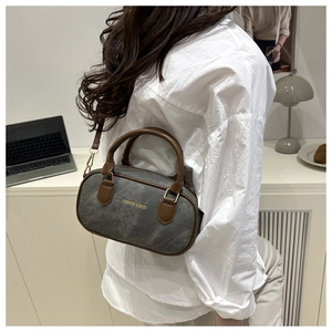 Detail of grey canvas Boston bag with brown leather handles and adjustable strap