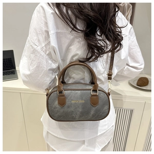 Macro shot of grey vintage fabric boston bag with brown leather handles and gold text logo