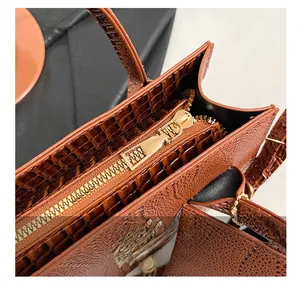 Detailed close-up of premium gold zipper and brown crocodile texture on the crossbody bag