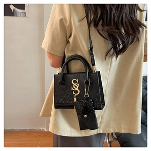 Fashionable black crocodile texture shoulder bag with gold S-buckle on a stylish model