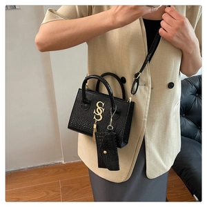 Detail of crocodile pattern handbag with gold metal hardware and mini pouch charm