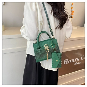 Green croc-effect handbag with gold tassel detail and small coin purse on a shoulder strap