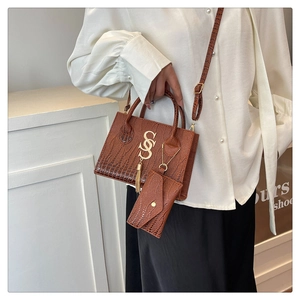 Close-up of brown crocodile texture handbag with golden S logo and metallic tassels