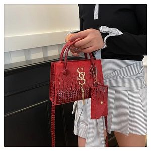 Macro shot of red faux crocodile leather texture with gold metal logo and tassel detail