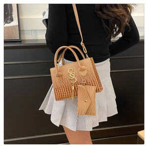 Brown crocodile texture handbag detail featuring gold logo and matching mini pouch
