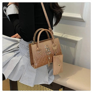 Detailed shot of brown croc-embossed handbag with gold hardware and tassel charm