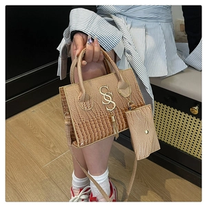 Detail of beige crocodile texture handbag with gold SS logo and matching mini pouch