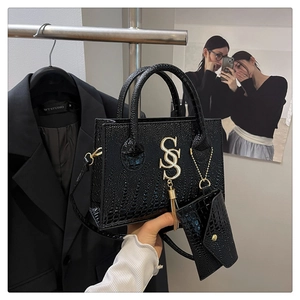 Detail of black croc-embossed handbag featuring gold hardware and detachable coin purse