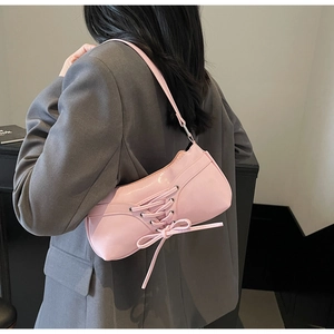 Detailed back view of pink PU shoulder bag with decorative lace-up and bow on a model