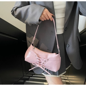Close-up of pink patent leather baguette bag featuring lace-up bow details