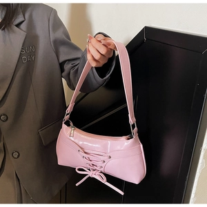 Detail of pink glossy ballet-style baguette bag with lace-up ribbon and bow decoration