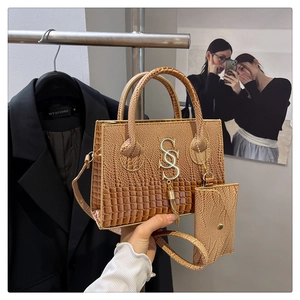 Detailed close-up of a brown crocodile pattern handbag set with a golden metal logo