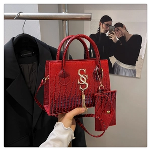 Close-up of red crocodile pattern handbag with gold SS logo and matching small wallet