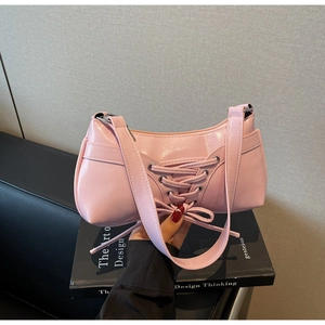 Detail of pink faux leather bag featuring ballet style lace-up design and bow decoration