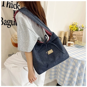 Detail of blue denim tote bag with red gingham lining and decorative bow on pocket