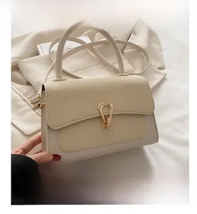 Detail of cream leather handbag with woven flap and curved gold metallic buckle