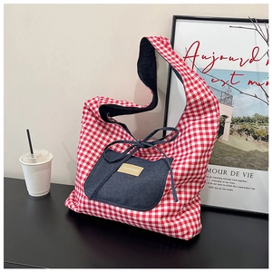 Detail of red checkered tote bag with denim pocket and fashion leather label detail