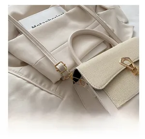 Detailed view of the gold U-shaped buckle on an off-white leather shoulder bag
