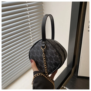 Détail d'un mini sac à main noir avec motif M gris, chaîne dorée et poignée élégante