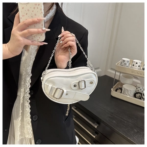 Detail of white heart-shaped leather crossbody bag with silver buckle and chain strap