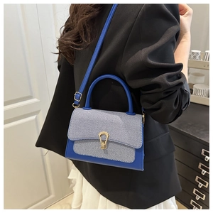Blue textured leather and denim crossbody bag with gold buckle shown on a model
