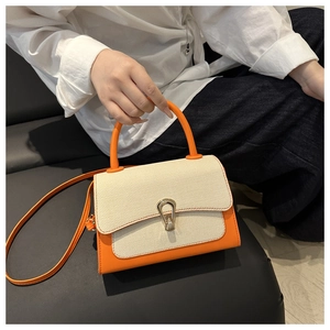 Detail of color-block crossbody bag with orange leather, canvas panel and gold lock clasp