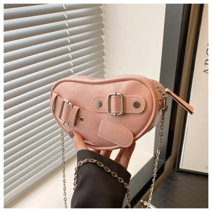 Detail of pink heart-shaped crossbody bag with vintage double buckles and silver chain