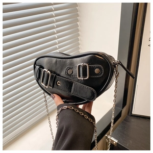 Close-up of black heart-shaped punk bag with silver studs and metal chain strap
