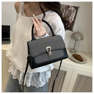 Detail of a chic two-tone crossbody bag with a metal U-buckle and tweed flap accent