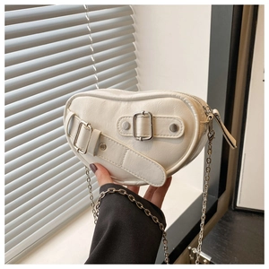 Close-up of white heart-shaped saddle bag with PU leather texture and metal chain
