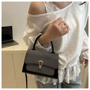 Detail of grey twill and leather handbag featuring a golden horseshoe metal lock buckle