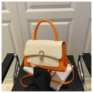 Detail of orange leather and cream woven textured small square bag with horseshoe buckle