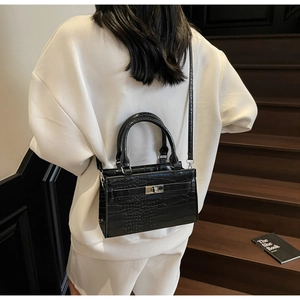 Detail of black crocodile texture handbag with silver twist lock and sturdy handle