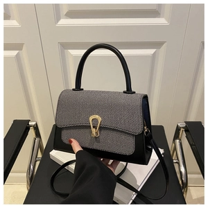 Detail of grey twill texture with black leather and golden horseshoe buckle on handbag