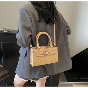 Detail of crocodile pattern leather bag with metallic twist lock on model back