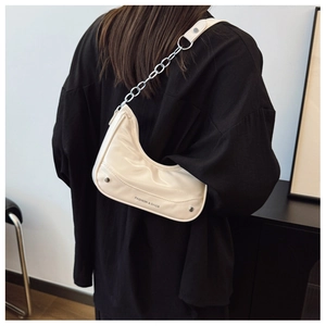 Close-up of cream crescent underarm bag with silver chain and fashion logo print