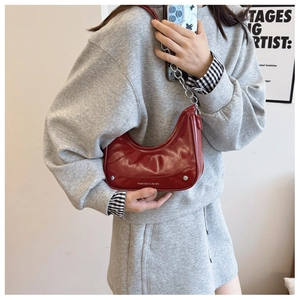 Detail of burgundy crescent bag with silver chain strap and metallic fashion buckle